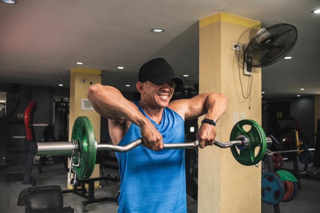 a man in blue top and black cap performing ez bar upright row