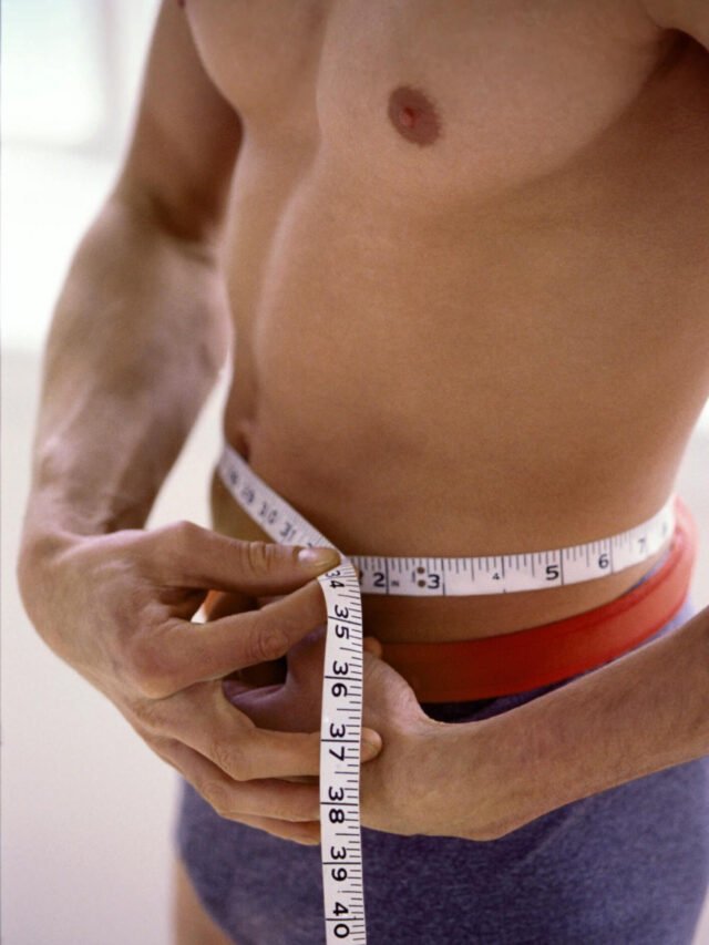 Man using a measuring tape to measure his waist circumference.