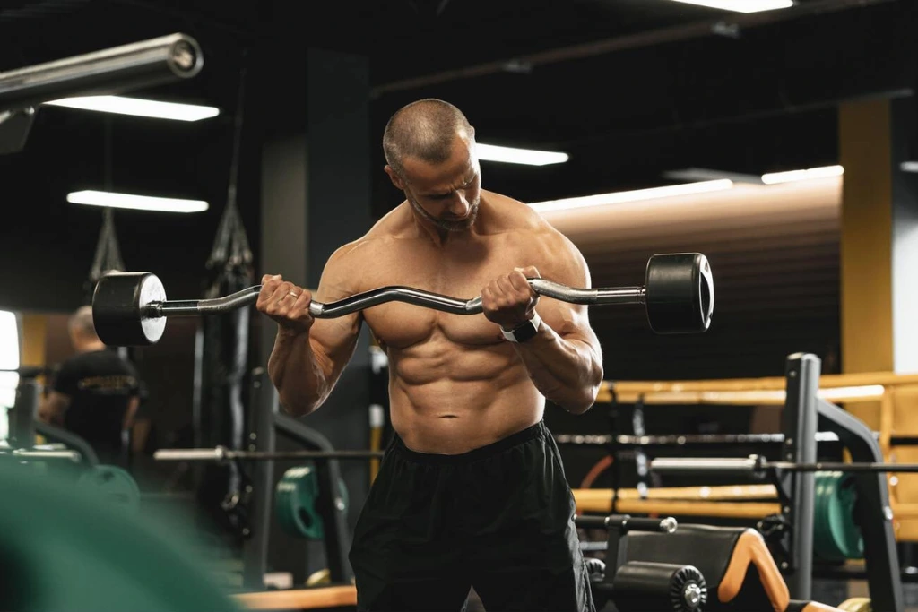 A man performing an Outside Grip Ez Bar Curl.